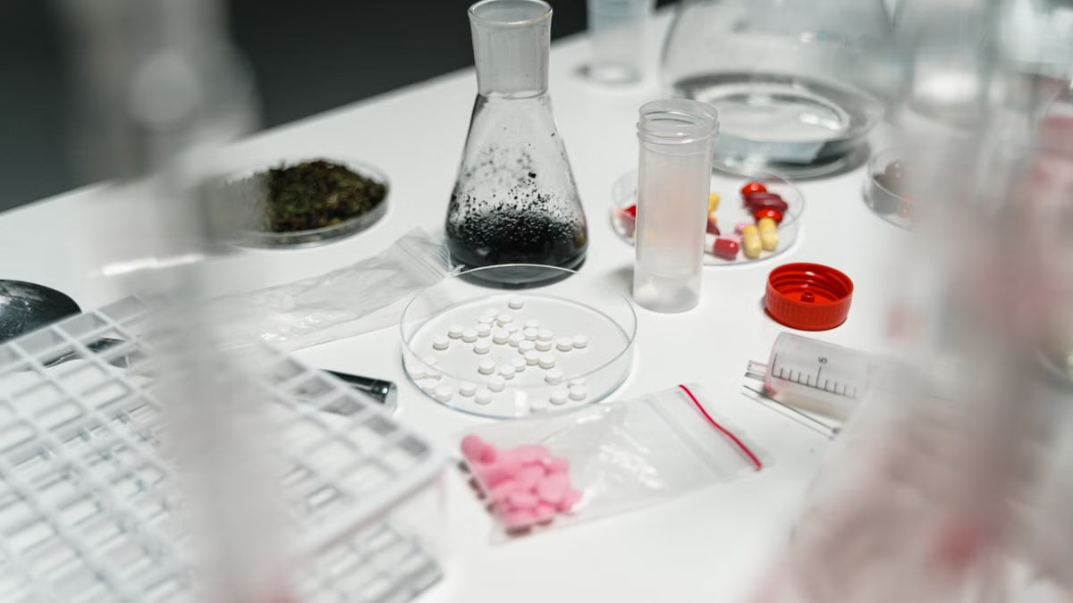 A laboratory table displaying pills, petri dishes, and chemical beakers for scientific research.
